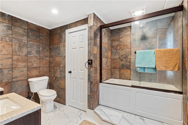 full bathroom with enclosed tub / shower combo, vanity, toilet, and tile walls