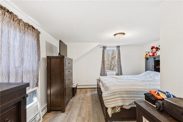 bedroom with baseboard heating and light hardwood / wood-style flooring