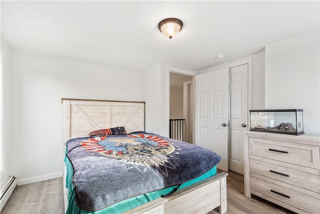 bedroom with baseboard heating and light hardwood / wood-style flooring