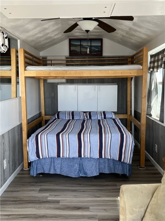 bedroom featuring wood walls, ceiling fan, and vaulted ceiling