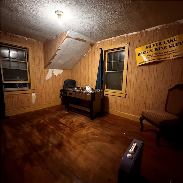 interior space with dark hardwood / wood-style floors, a textured ceiling, wooden walls, and lofted ceiling