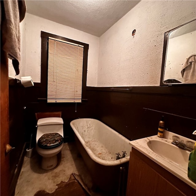 bathroom with toilet, a tub to relax in, vanity, and a textured ceiling