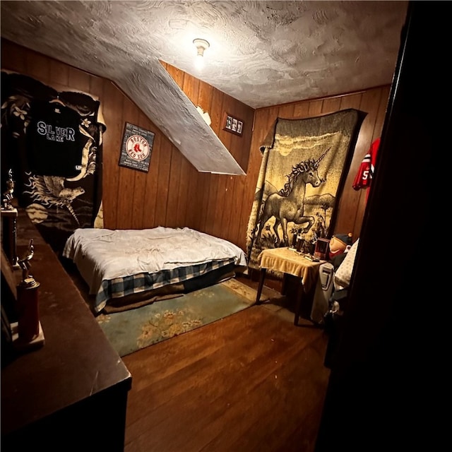 bedroom with wooden walls, wood-type flooring, and lofted ceiling