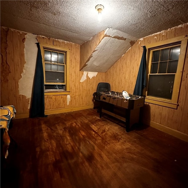 bedroom with wooden walls, a textured ceiling, vaulted ceiling, and dark hardwood / wood-style floors