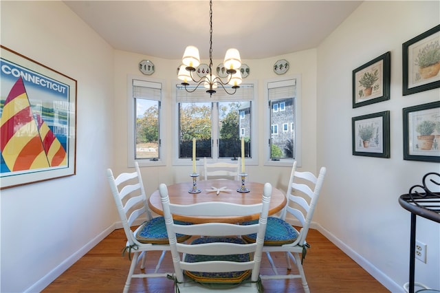 dining space with hardwood / wood-style floors and a notable chandelier