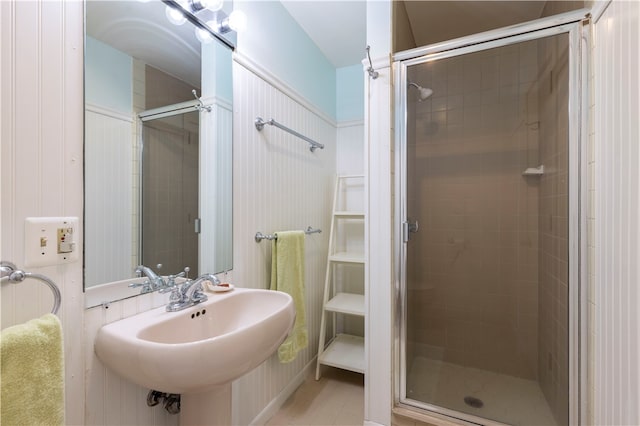 bathroom featuring a shower with shower door, tile patterned flooring, and sink