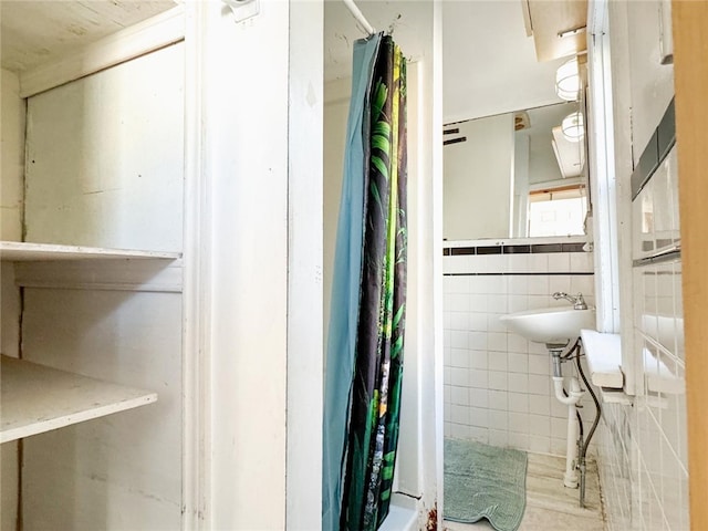 bathroom with walk in shower, sink, and tile walls