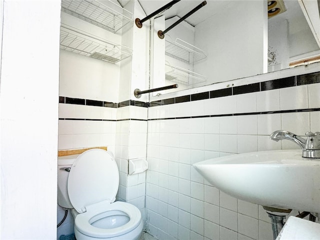 bathroom featuring sink, toilet, and tile walls