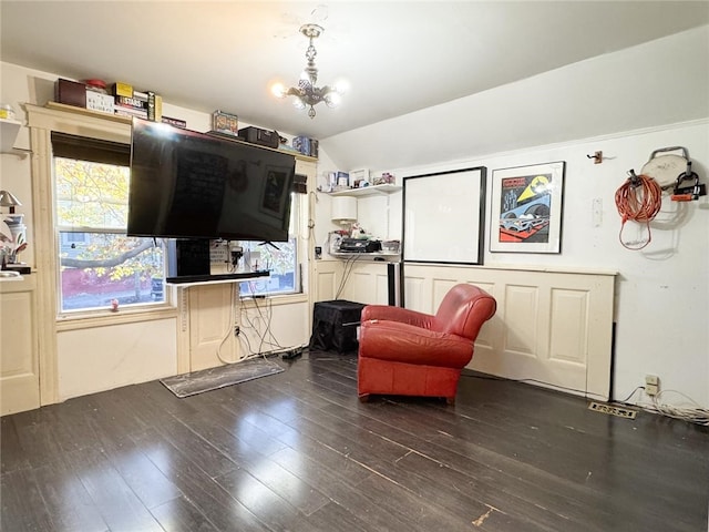 living area with dark wood-type flooring, a chandelier, and vaulted ceiling