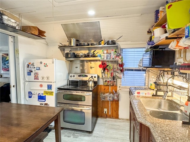 kitchen with light stone countertops, sink, and electric range