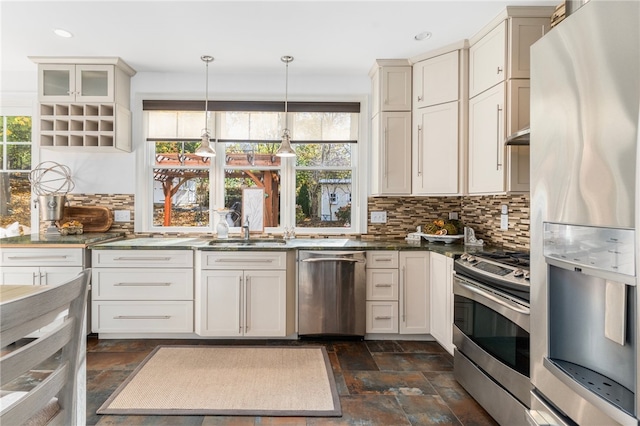 kitchen featuring sink, appliances with stainless steel finishes, tasteful backsplash, dark stone countertops, and pendant lighting