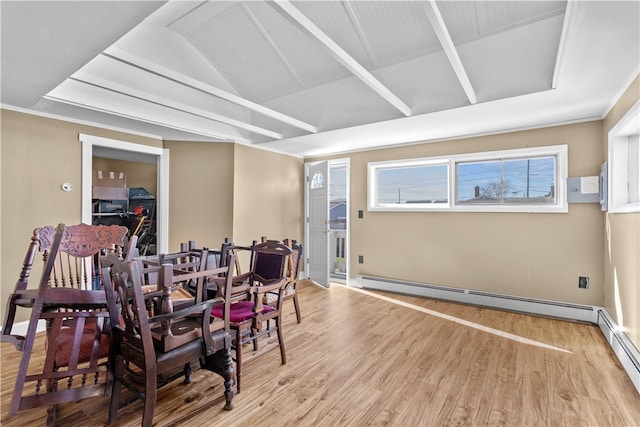 dining space featuring light hardwood / wood-style flooring, vaulted ceiling, and a baseboard heating unit