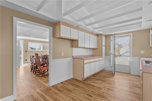 kitchen with beam ceiling, light hardwood / wood-style floors, and plenty of natural light