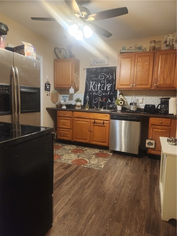 kitchen with appliances with stainless steel finishes, backsplash, dark wood-type flooring, and sink