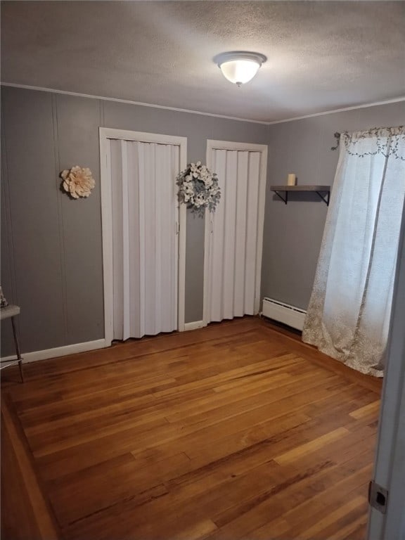 interior space with a textured ceiling, hardwood / wood-style flooring, and a baseboard heating unit