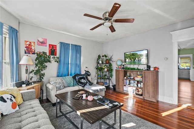 living room featuring dark wood-type flooring and ceiling fan