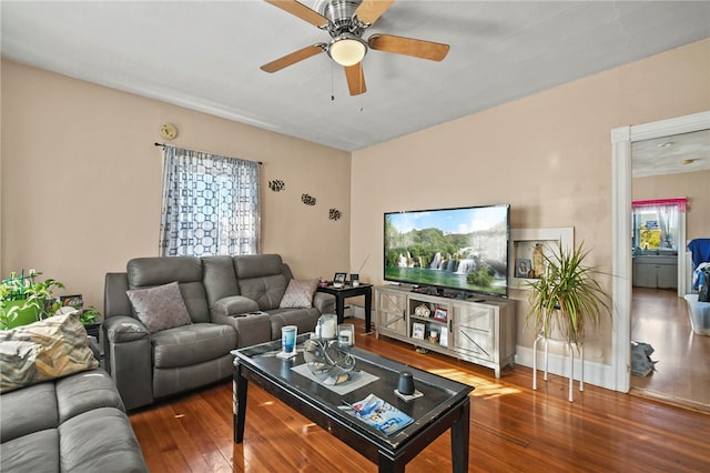 living room with dark wood-type flooring and ceiling fan