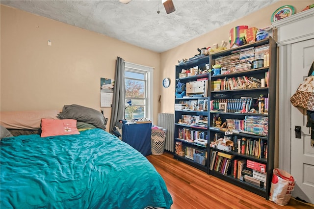 bedroom with hardwood / wood-style floors, ceiling fan, and a textured ceiling