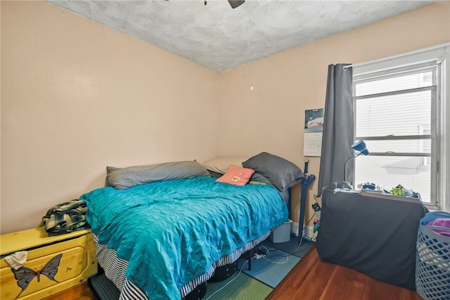 bedroom with ceiling fan, wood-type flooring, and a textured ceiling