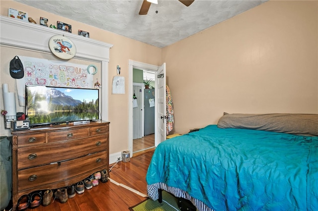 bedroom with a textured ceiling, wood-type flooring, and ceiling fan