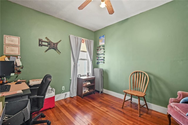 home office featuring hardwood / wood-style flooring, ceiling fan, and radiator