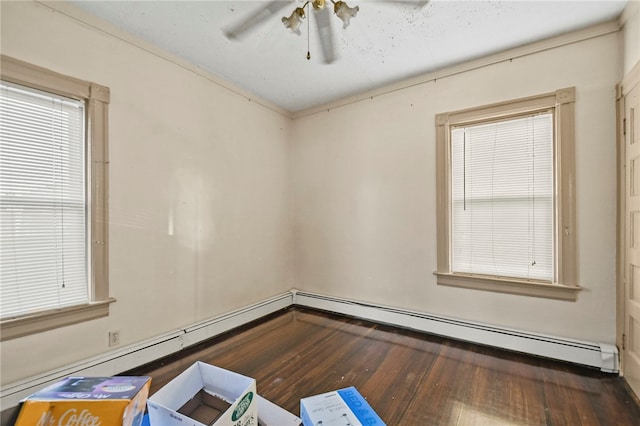 empty room with a baseboard heating unit, dark wood-type flooring, and ceiling fan