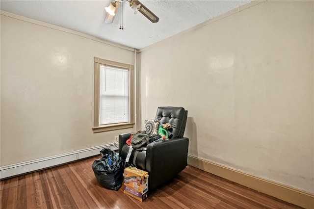 living area featuring baseboard heating, a textured ceiling, dark hardwood / wood-style floors, and ceiling fan