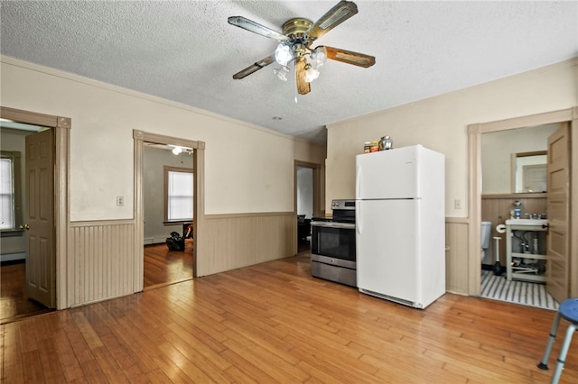 kitchen featuring light hardwood / wood-style floors, stainless steel stove, white refrigerator, and a textured ceiling