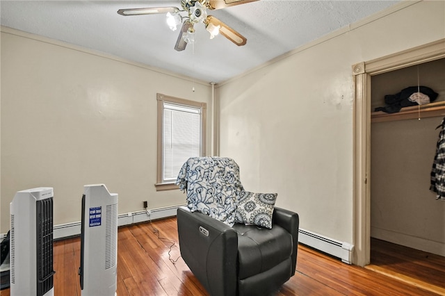 living area with hardwood / wood-style floors, ceiling fan, and a baseboard heating unit