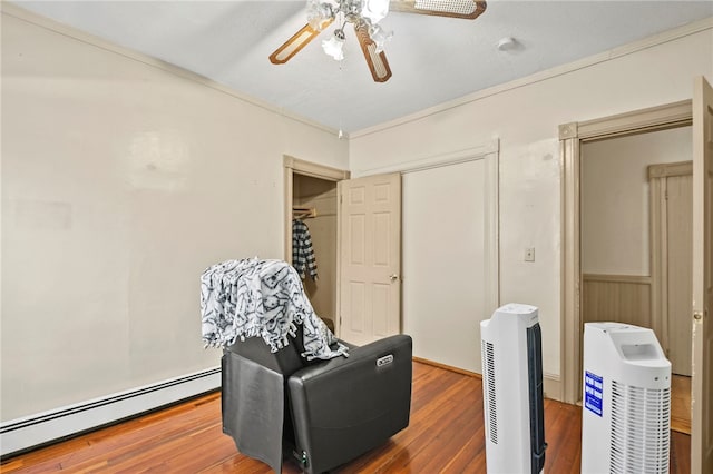 sitting room featuring hardwood / wood-style floors, ceiling fan, a baseboard heating unit, and ornamental molding