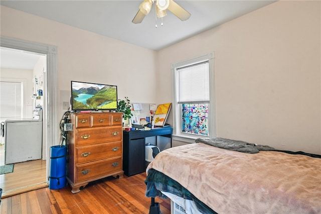 bedroom with washer and dryer, hardwood / wood-style flooring, and ceiling fan