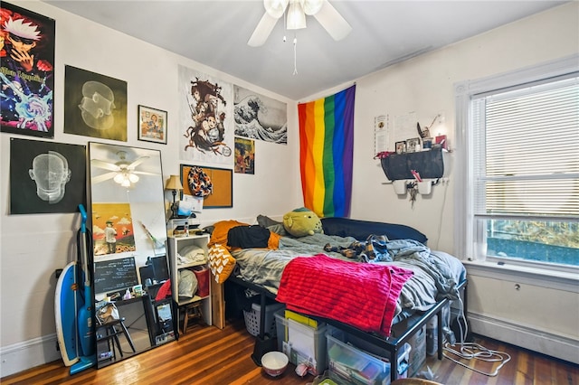 bedroom featuring dark wood-type flooring, ceiling fan, and a baseboard heating unit