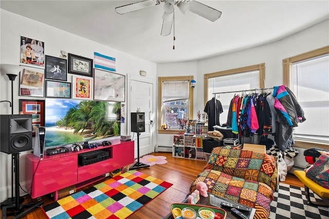 rec room featuring hardwood / wood-style flooring, ceiling fan, and a baseboard radiator