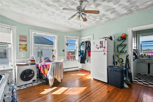 interior space with a baseboard heating unit, wood-type flooring, ceiling fan, and white refrigerator