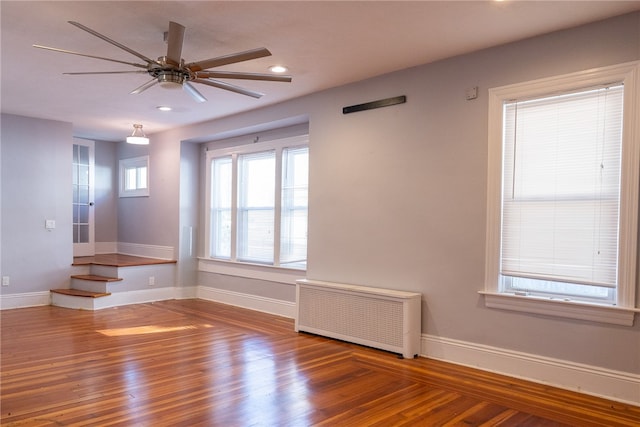 empty room featuring radiator heating unit, hardwood / wood-style flooring, and ceiling fan