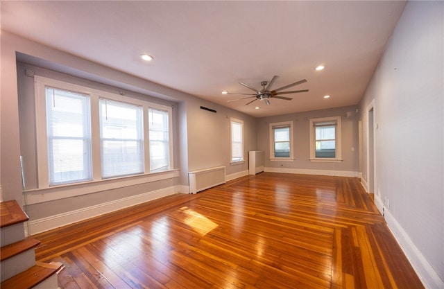 spare room featuring hardwood / wood-style floors, ceiling fan, and radiator