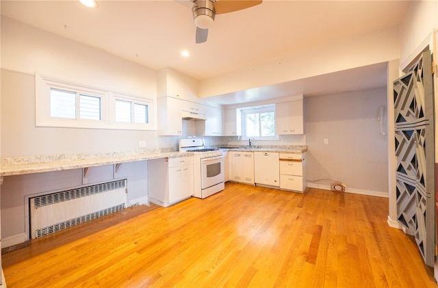 kitchen featuring gas range gas stove, white cabinetry, ceiling fan, radiator heating unit, and light hardwood / wood-style flooring