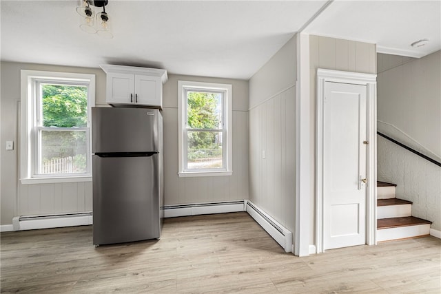 kitchen featuring white cabinets, stainless steel fridge, baseboard heating, and light wood-type flooring