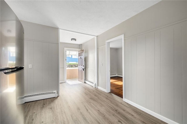 hall with baseboard heating and light hardwood / wood-style floors