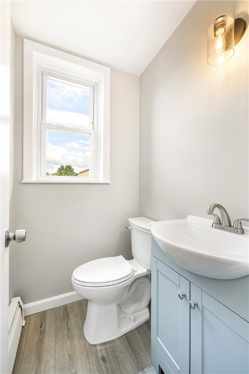 bathroom with wood-type flooring, vanity, a baseboard radiator, toilet, and lofted ceiling