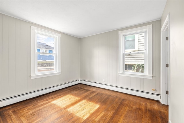 spare room featuring dark wood-type flooring, a healthy amount of sunlight, and a baseboard radiator