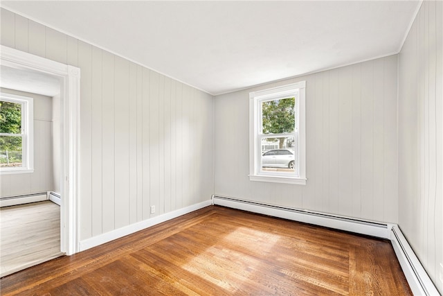 empty room with hardwood / wood-style floors and a baseboard radiator