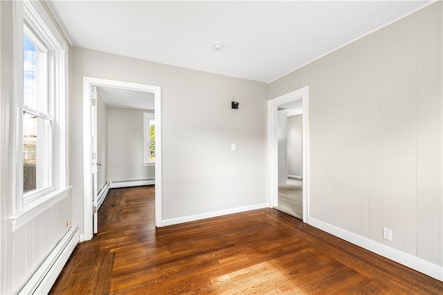 empty room featuring dark wood-type flooring and a baseboard radiator