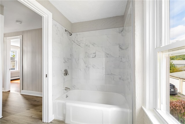 bathroom with a baseboard heating unit, tiled shower / bath, and hardwood / wood-style flooring