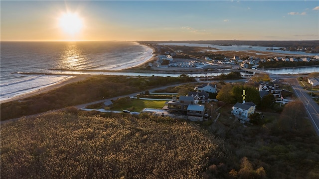 aerial view at dusk featuring a water view and a beach view