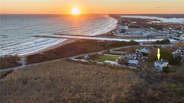 aerial view at dusk featuring a water view and a view of the beach