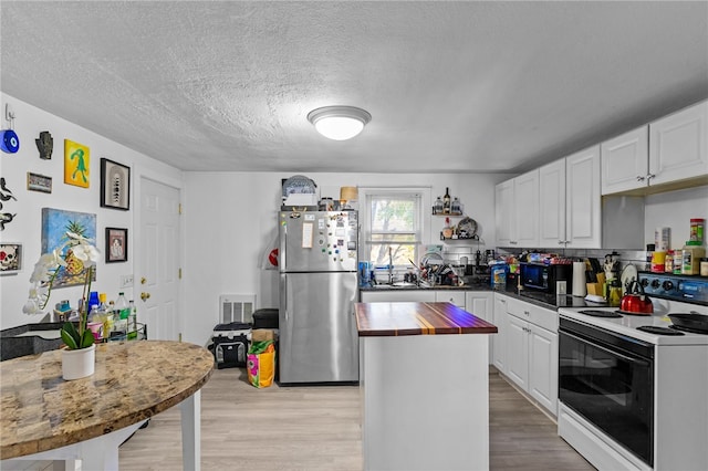 kitchen featuring electric stove, stainless steel fridge, white cabinets, and light wood-type flooring