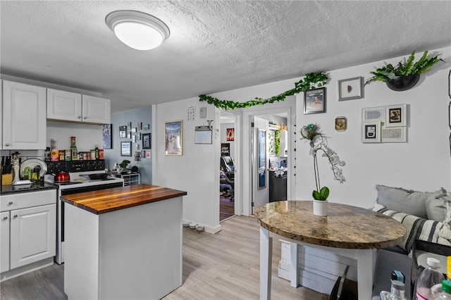 kitchen featuring a textured ceiling, light hardwood / wood-style floors, and white cabinetry