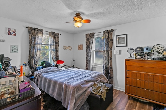 bedroom featuring ceiling fan, dark hardwood / wood-style flooring, and a textured ceiling