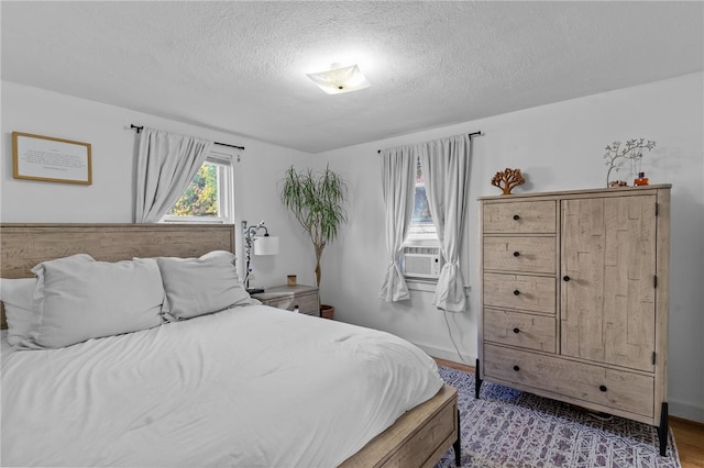 bedroom featuring cooling unit, light hardwood / wood-style floors, and a textured ceiling